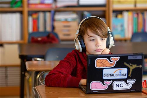 Boy at desk with headphones on watching computer
