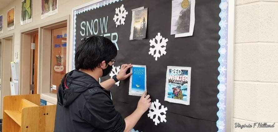 Student stapling items to bulletin board