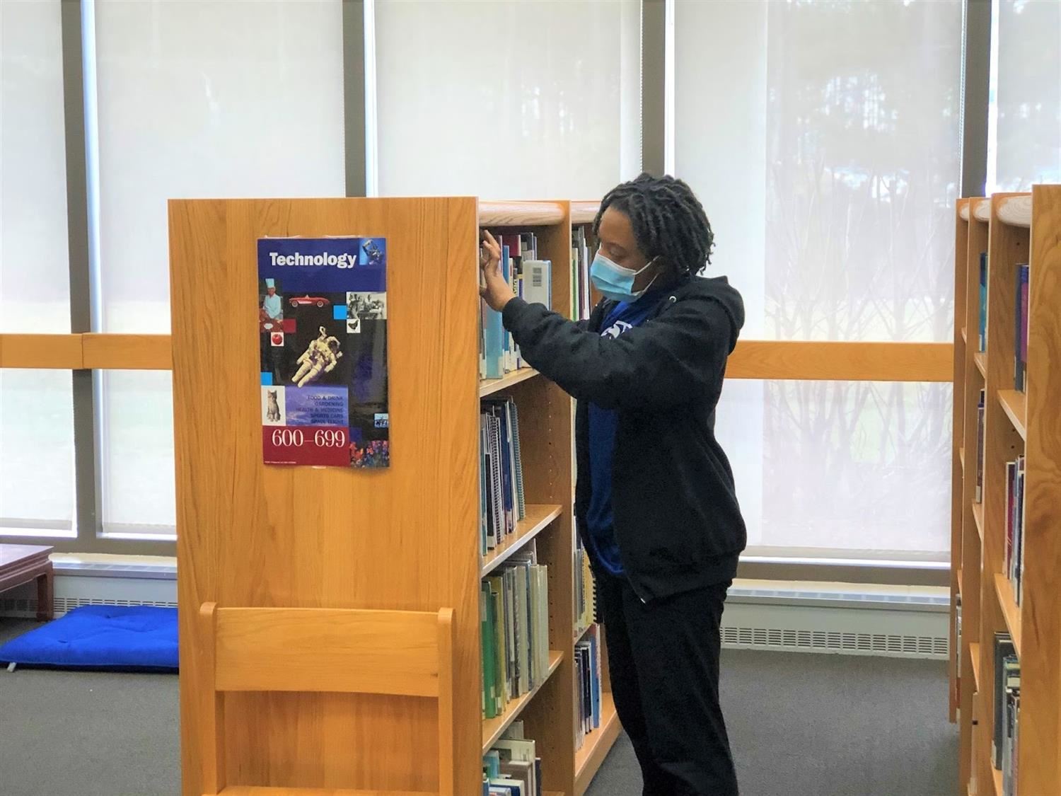 Student looking a library shelf