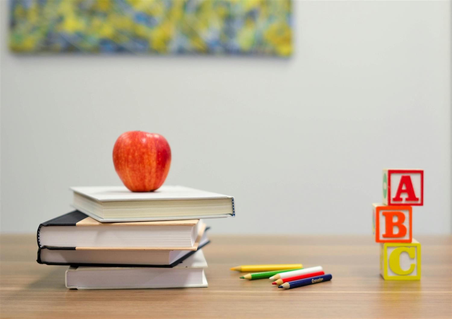 Table with books, an apple, colored pencils and ABC blocks on it